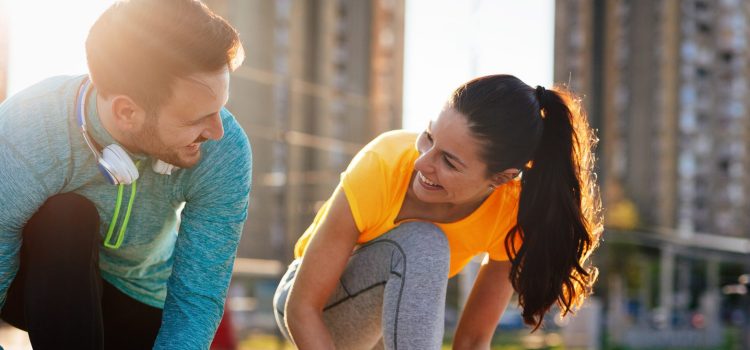 Couple smiling at each other while outside about to go on a run.