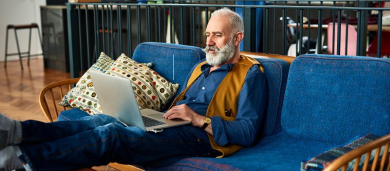 A retiree relaxes on a couch
with his laptop.