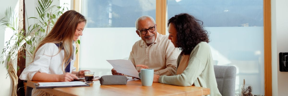 A retired couple meets with an agent to review paperwork.