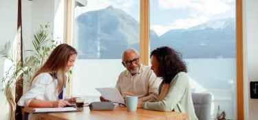A retired couple meets with an agent to review paperwork.