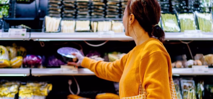 A woman chooses items from the produce section of a supermarket.