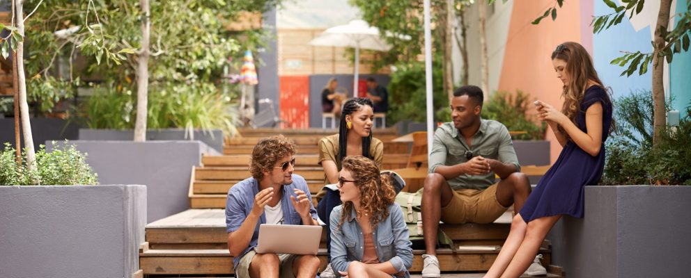 Group of friends sit on stairs outside while hanging out and talking