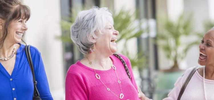 Group of three women laughing outside.