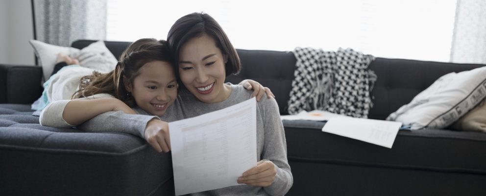 A mother and her daughter sit on a couch.