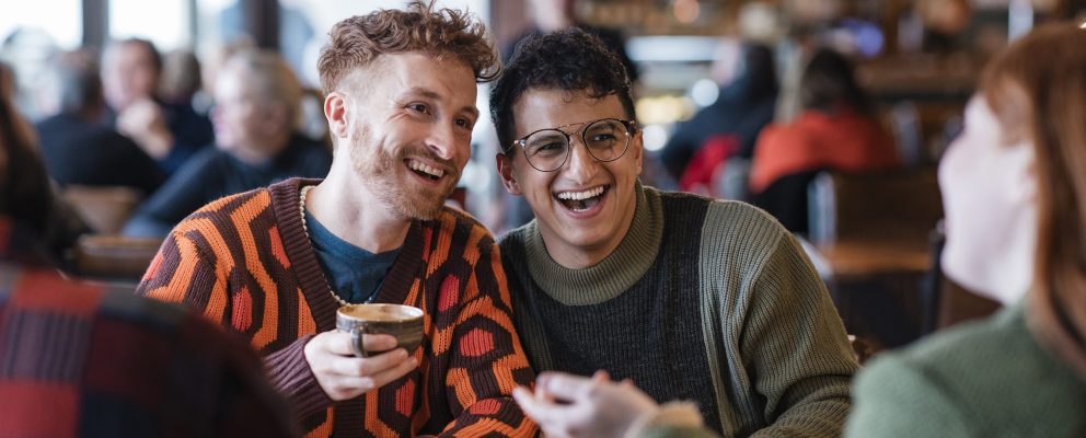 Two young men chat with friends in a crowded café.