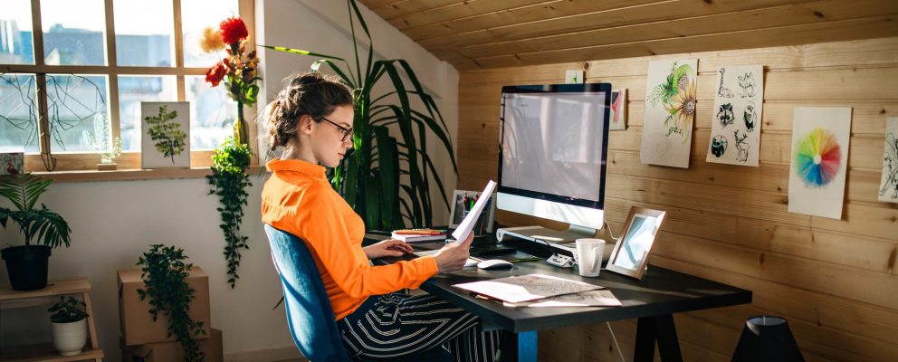A woman looks at a piece of paper while working at her desk