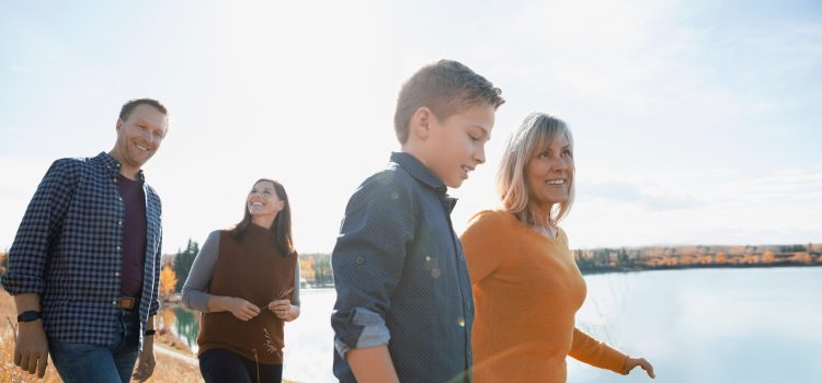 Four people walking and talking by the water.