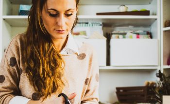A woman sits at her desk cutting paper