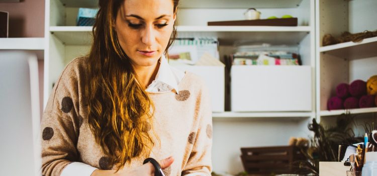 A woman sits at her desk cutting paper