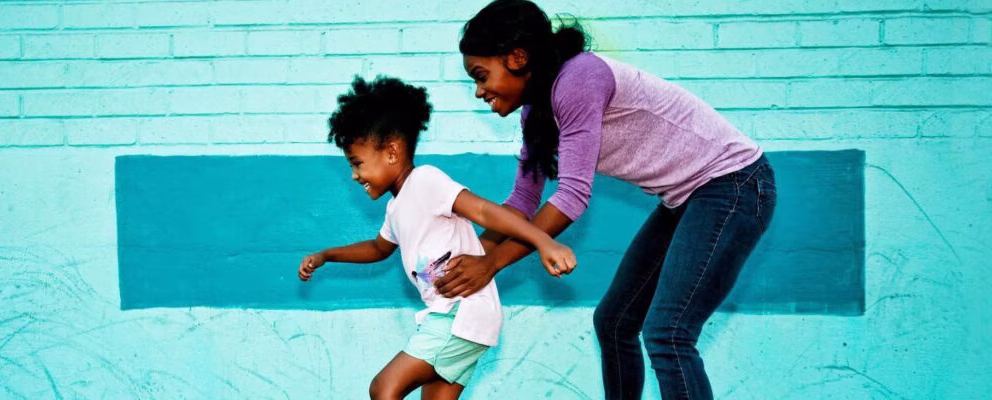 Woman helping her daughter learn how to roller skate.