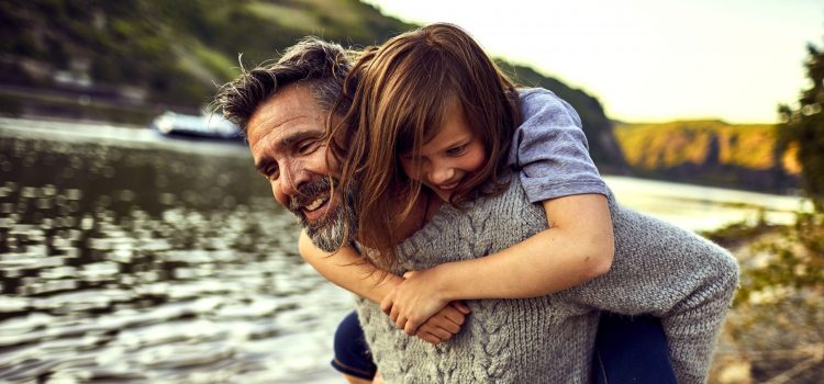 A father gives his daughter a piggyback ride.